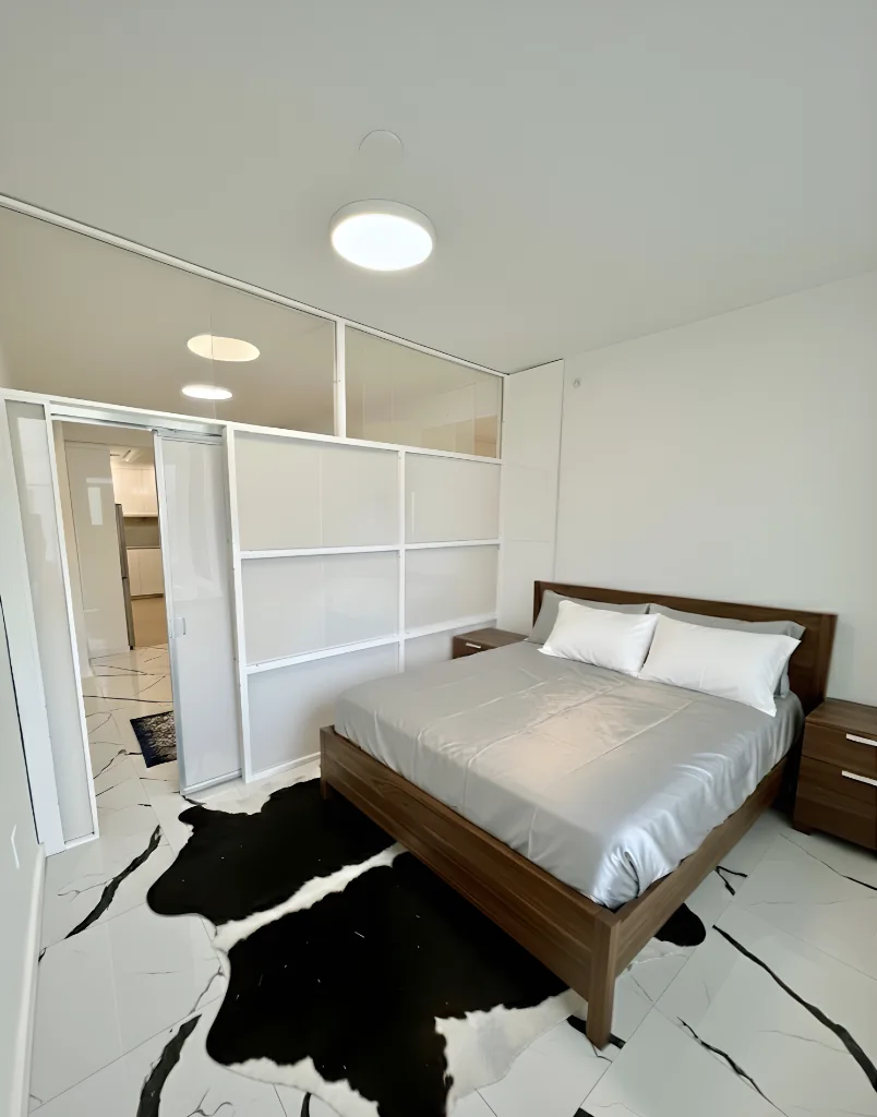 NYC studio converted to bedroom with 1W2R white freestanding wall system — sliding panel, no construction
