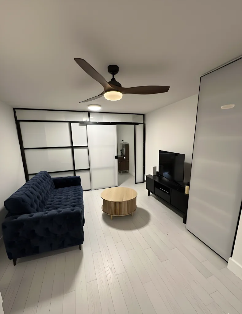 NYC apartment living room with navy sofa and 1W2R black-frame freestanding glass partition wall