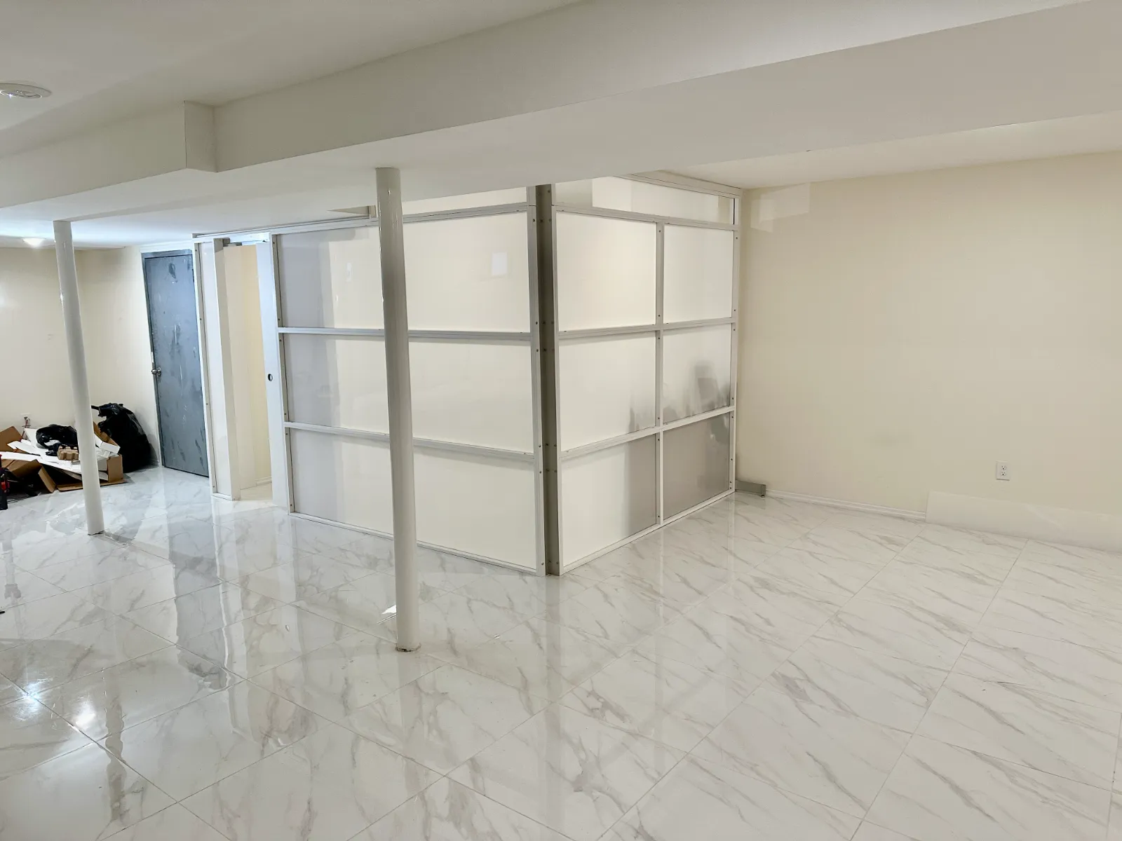 L-shaped freestanding basement room divider with frosted panels enclosing a corner room